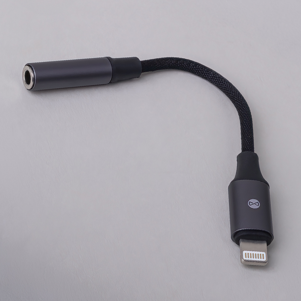 Egy adapter szürke testtel és fekete fonott kábellel. Fejhallgató-csatlakozóval rendelkezik az egyik végén, a másikon Lightning csatlakozóval.