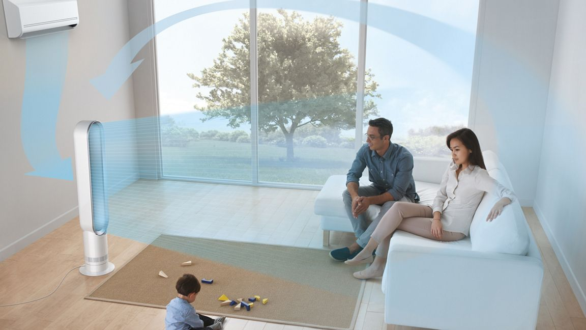 Une famille dans un salon moderne avec un ventilateur et un climatiseur. Un enfant joue avec des jouets sur le tapis.