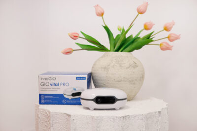 Białe urządzenie medyczne, pudełko i wazon z różowymi tulipanami na białej powierzchni. Tło jest białe.