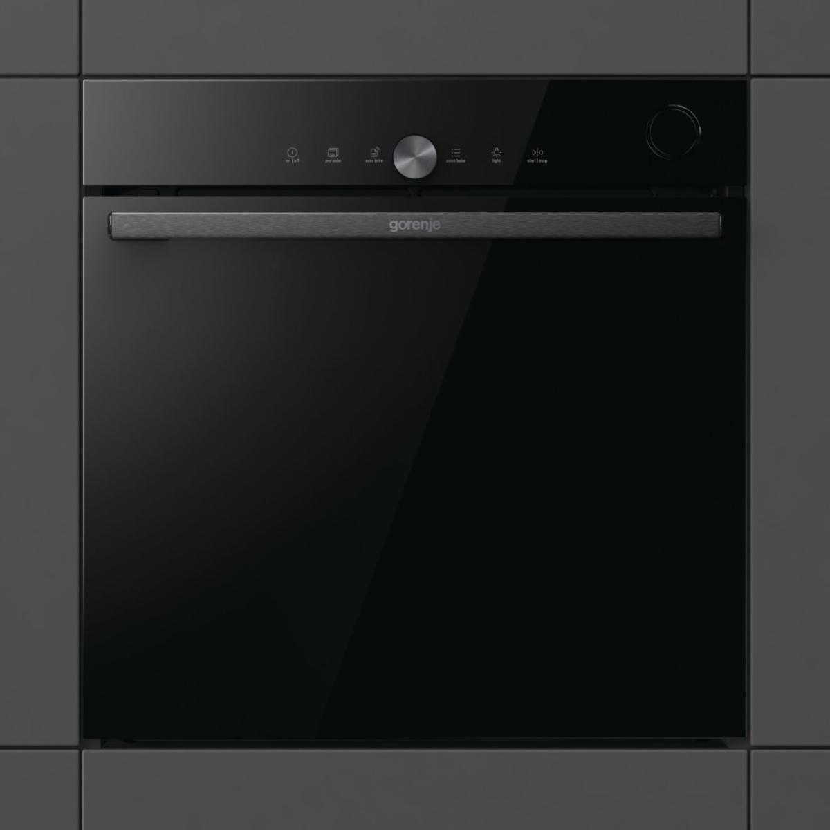 Fekete Gorenje sütő sötétszürke falba építve. Fogantyú, vezérlőpanel és üvegajtó. A márkanév látható.