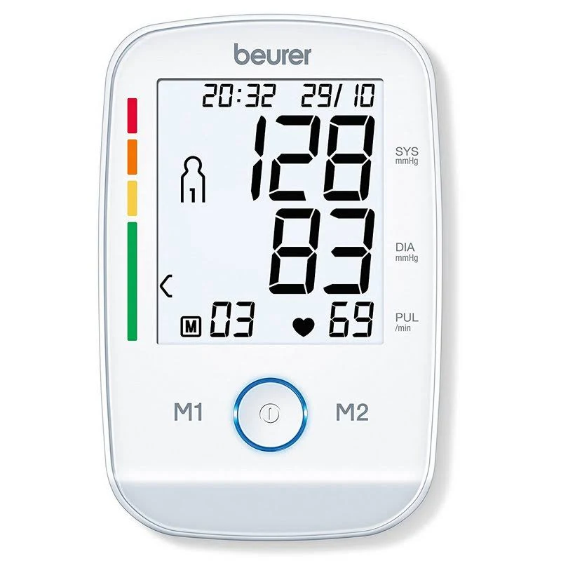 Un monitor de presión arterial blanco muestra lecturas: 128/83, pulso 69 y hora. Tiene un indicador de salud codificado por colores y botones.