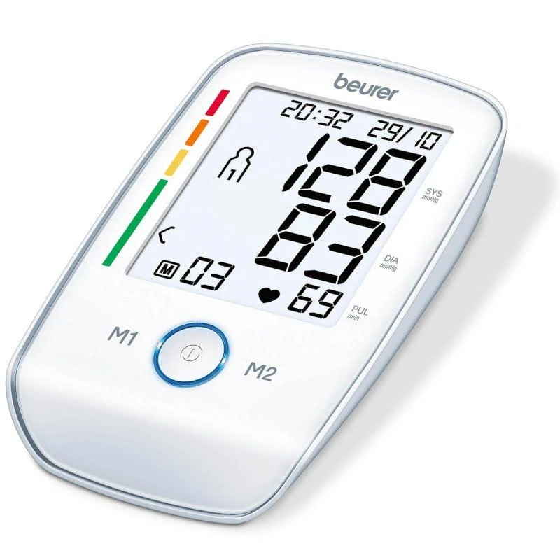 Un monitor de presión arterial Beurer blanco muestra lecturas: 128/83, pulso 69. Hora: 20:32, fecha: 29/10. Botones M1, M2.