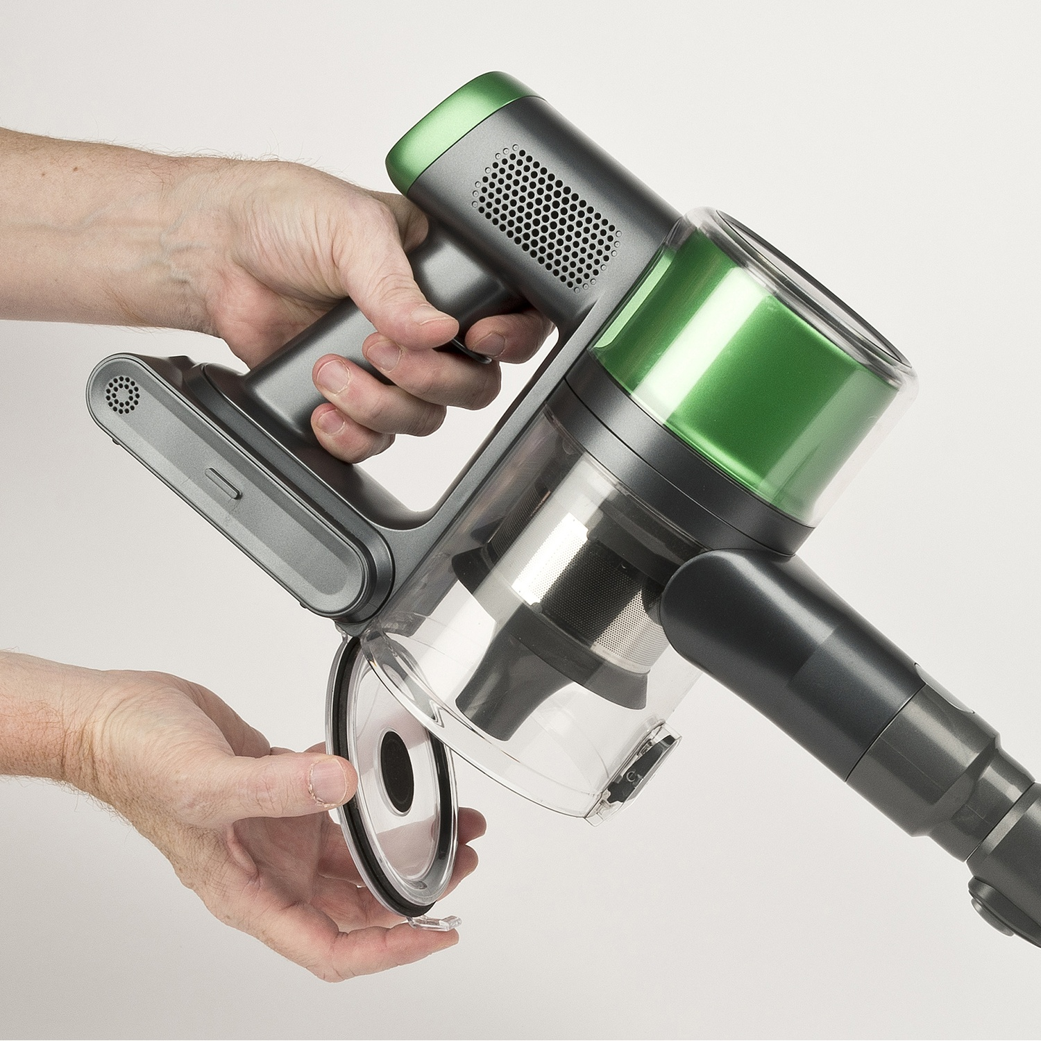 Le mani tengono un aspirapolvere senza fili verde e grigio smontato su sfondo bianco.