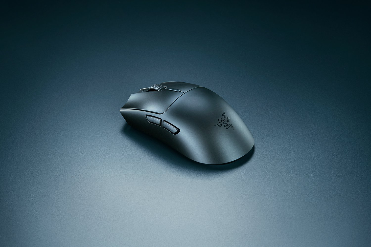Egy fekete Razer gamer egér sötét felületen. Az egéren gombok és görgő van. Razer logó az oldalon.