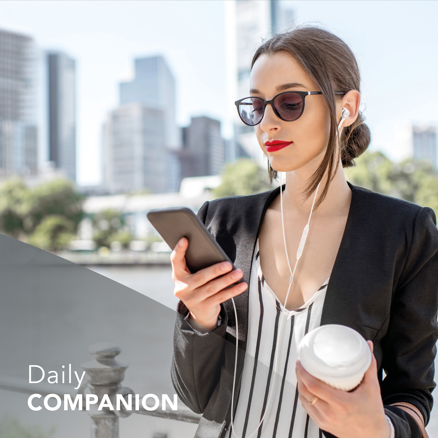 Mujer con gafas de sol sosteniendo teléfono y café, con blazer. Rascacielos al fondo, día soleado.
