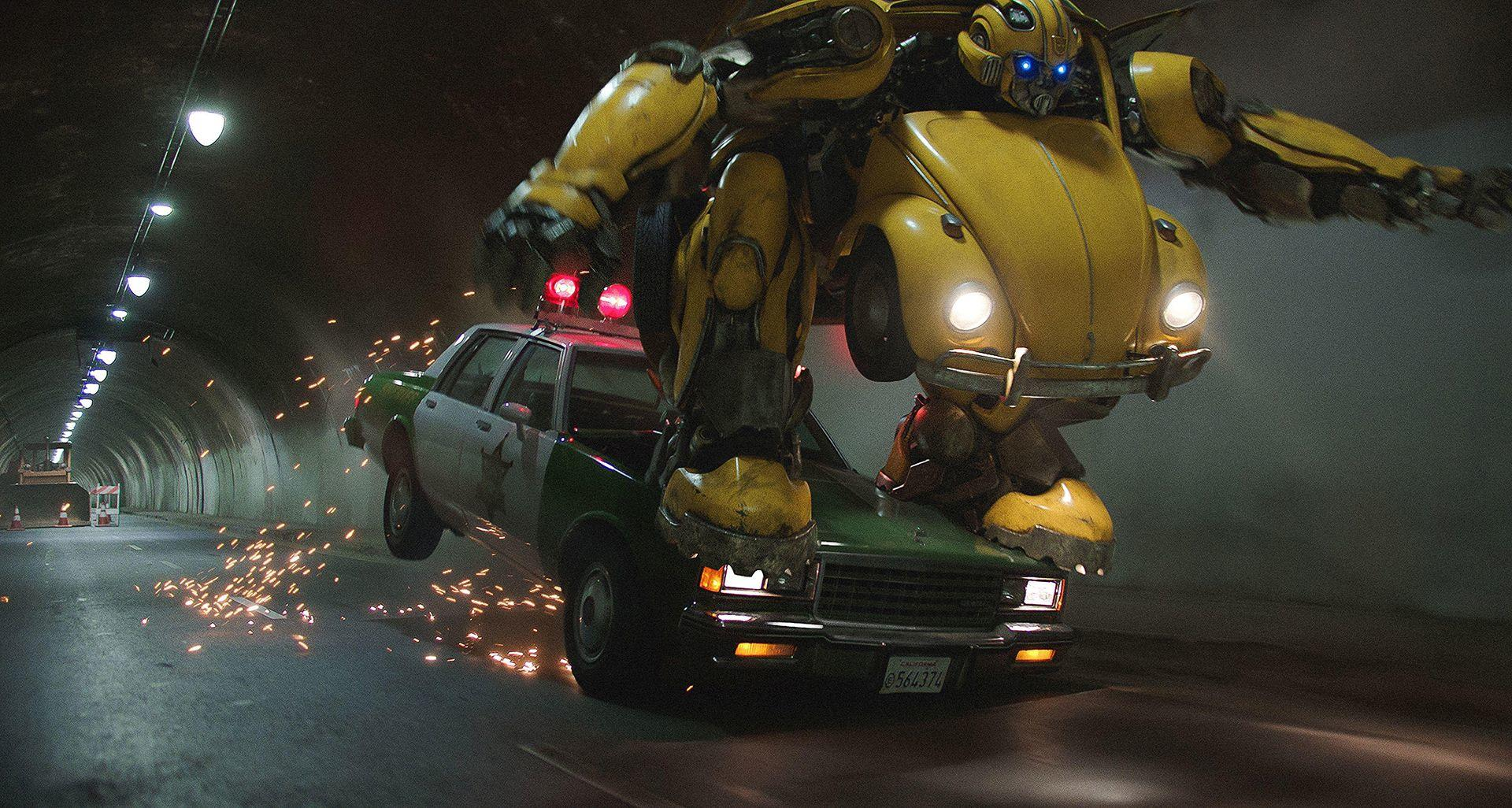 Bumblebee-Roboter springt über einen Polizeiwagen in einem Tunnel. Funken und Lichter erhellen die Szene. Actionreiche Filmszene.