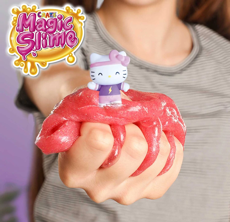Egy személy piros csillámos nyálkát tart, tetején egy Hello Kitty figurával. A háttérben egy 'Magic Slime' logó látható.
