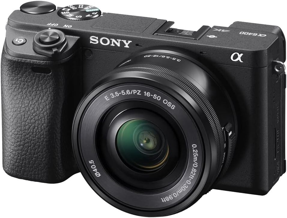 Siyah bir Sony kamera, mercek, kadranlar ve düğmeler. Mercek yeşil yansımaya sahip. Kamera beyaz bir arka plan üzerinde.