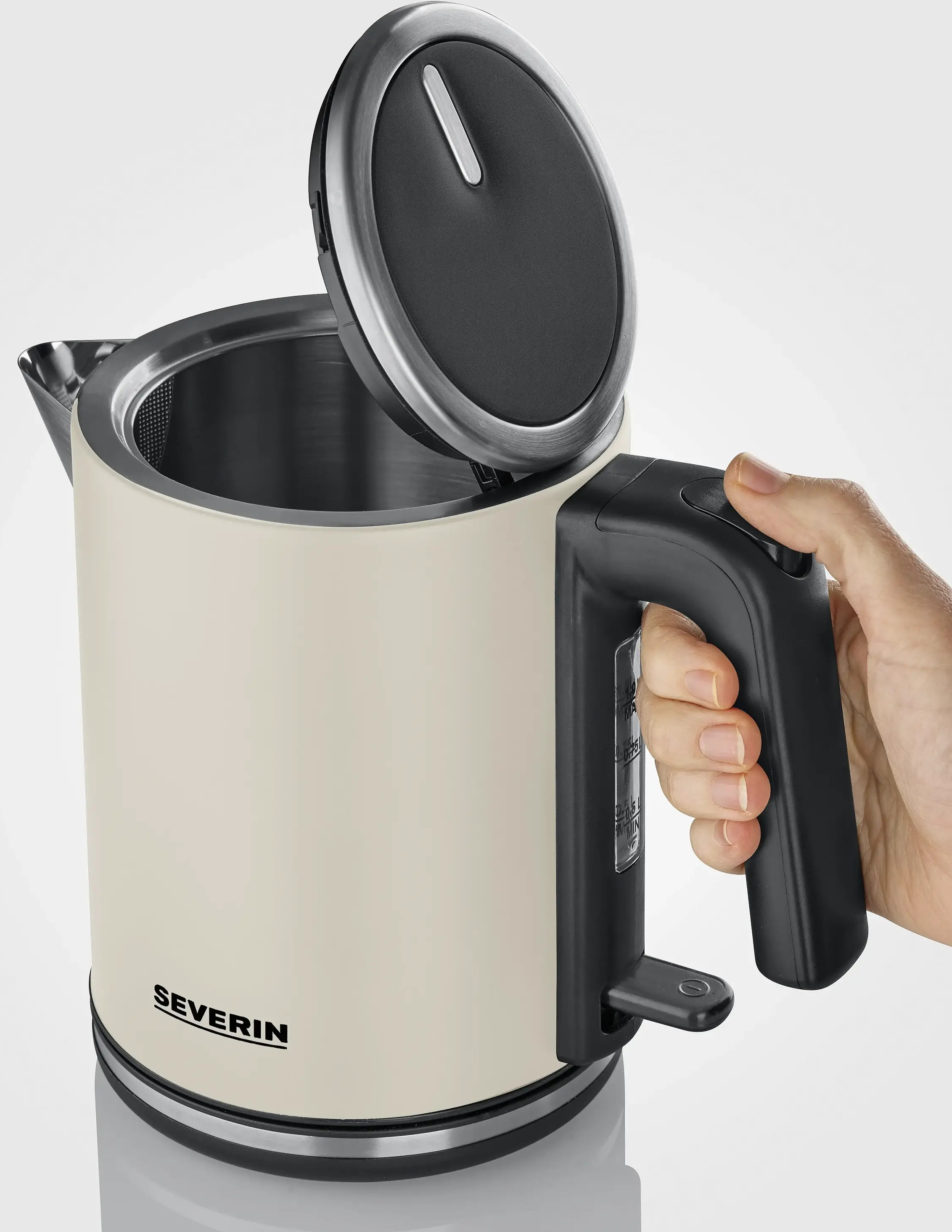 Kremowy czajnik elektryczny z otwartą pokrywą. Ręka trzyma uchwyt. Widoczna nazwa marki.