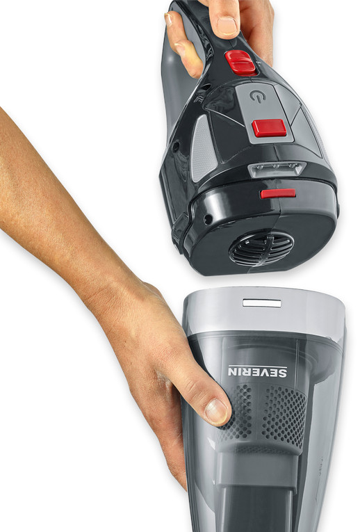 Ręce trzymają czarno-szary odkurzacz ręczny. Pojemnik na kurz jest osobny.