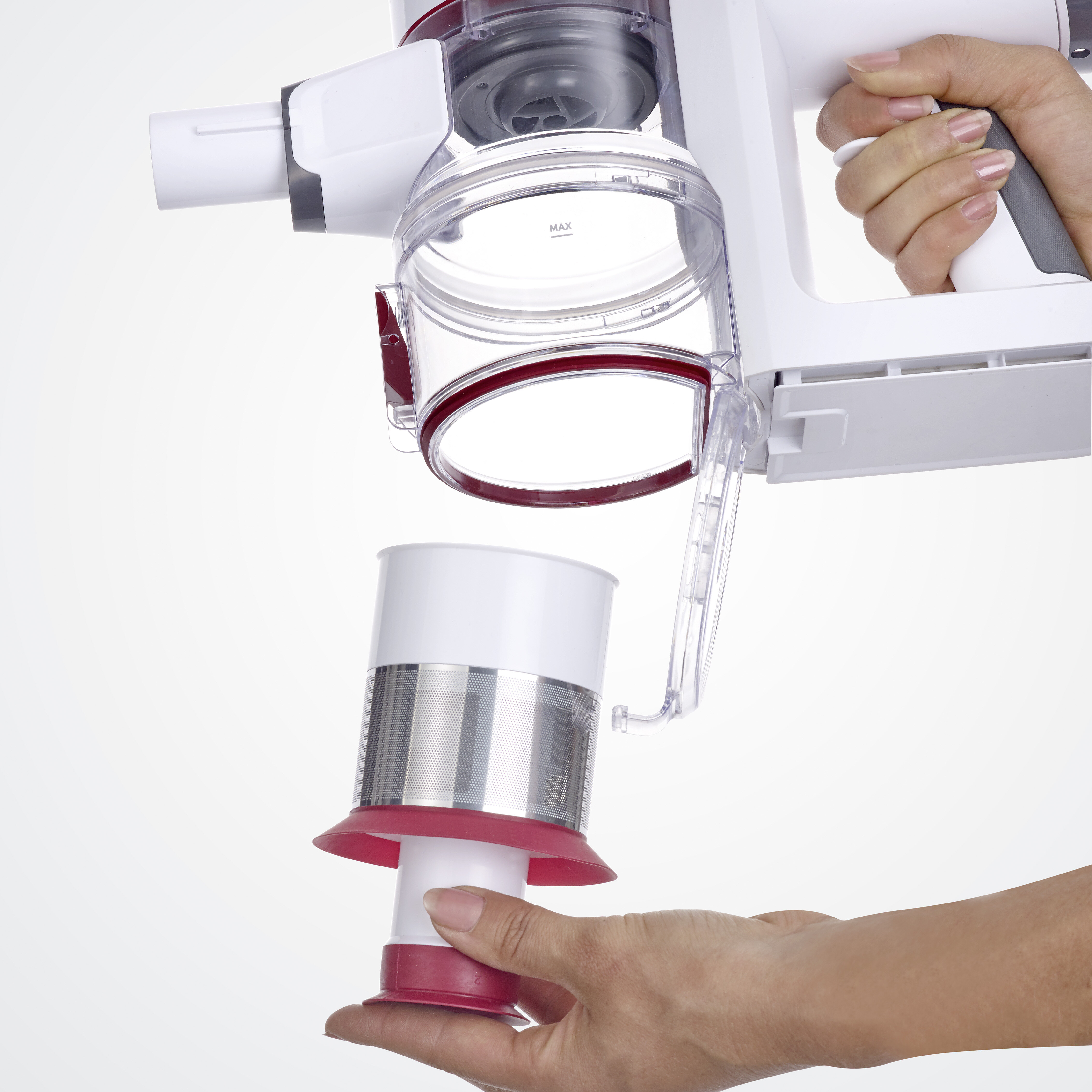 Ręce osoby demontują biało-czerwony odkurzacz. Pojemnik na kurz jest wyjmowany z uchwytu.