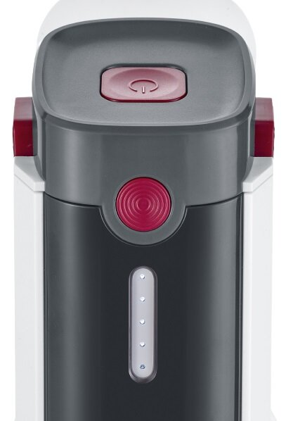 Zbliżenie białego, szarego i czerwonego urządzenia. Posiada przycisk zasilania i okrągły czerwony przycisk. Widoczny jest wskaźnik poziomu wody.