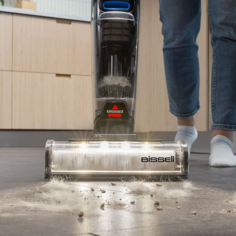 Osoba odkurza podłogę odkurzaczem Bissell. Zbierane są zanieczyszczenia. Osoba ma na sobie dżinsy i skarpetki.