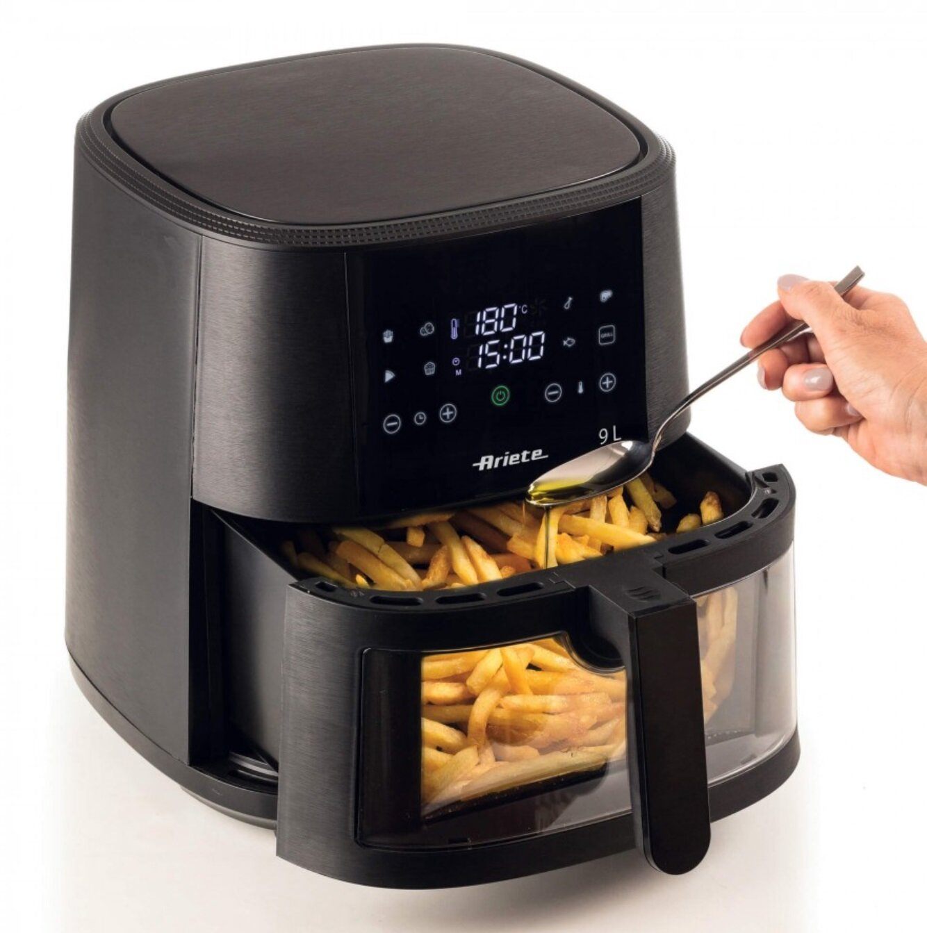 Czarna frytownica z frytkami w środku. Ręka nalewa olej łyżką. Wyświetlacz pokazuje ustawienia.