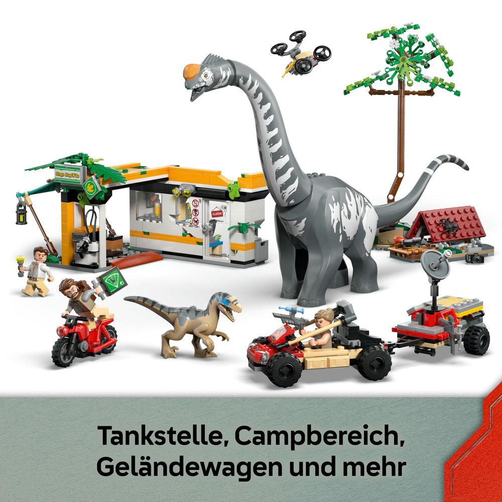 Eine Spielzeugszene mit Dinosaurier, Tankstelle, Fahrzeugen und Figuren, alle aus Bausteinen, vor weißem Hintergrund.