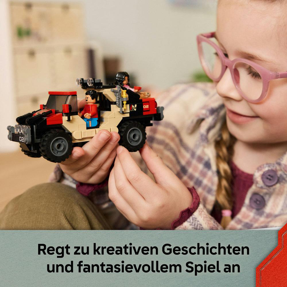 Ein Mädchen mit rosafarbener Brille hält ein Spielzeugauto mit Figuren. Das Auto ist beige, rot und schwarz. Der Hintergrund ist unscharf.