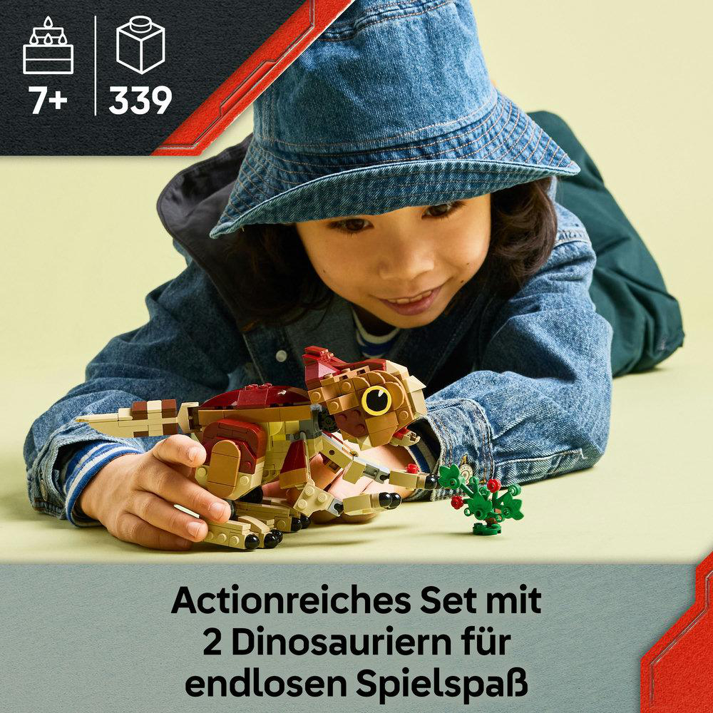Ein Kind in Jeansjacke und Hut hält einen Lego-Dinosaurier. Der Hintergrund umfasst ein rotes Dreieck und Text.