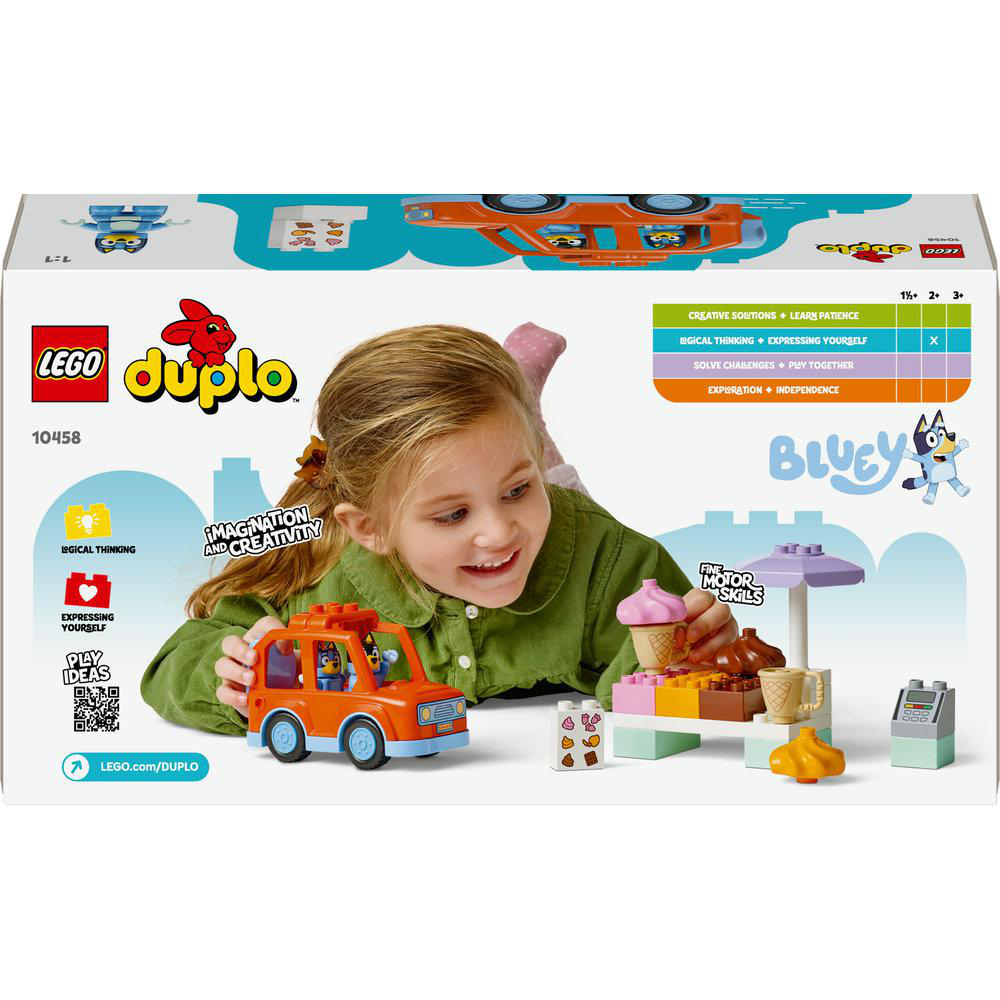 Ein Mädchen hält ein orangefarbenes Lego Duplo-Auto. Hinter ihr befindet sich eine Lego-Set-Box mit Bluey-Motiv und Eis.