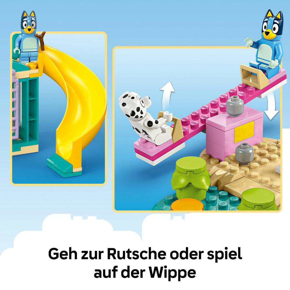 Eine Lego-Szene mit Bluey und einem Dalmatiner auf einer Rutsche und einer Wippe. Auf sandigem Untergrund mit grünen Büschen.