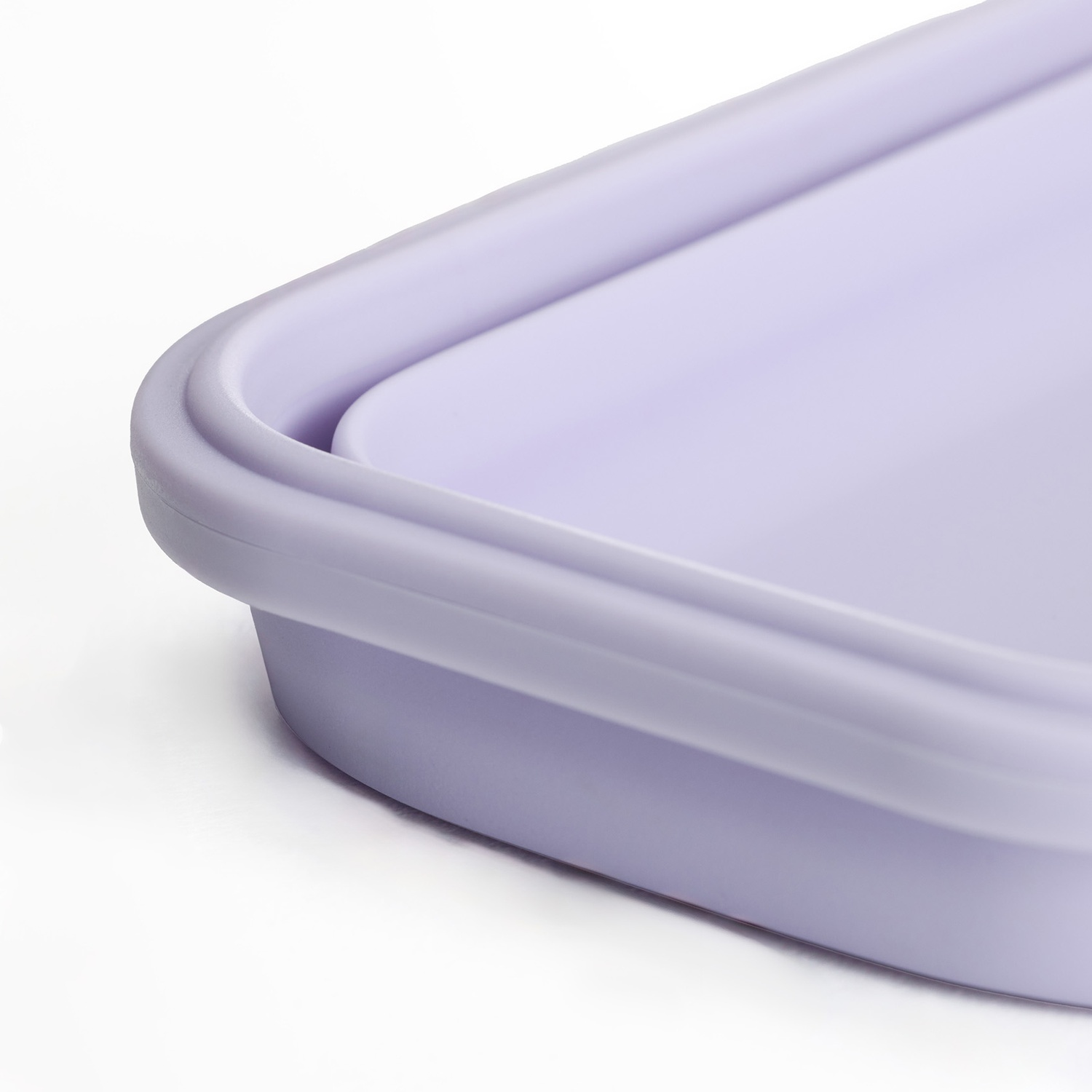 Primo piano di un contenitore rettangolare viola chiaro. Il contenitore ha bordi arrotondati e si trova su una superficie bianca.
