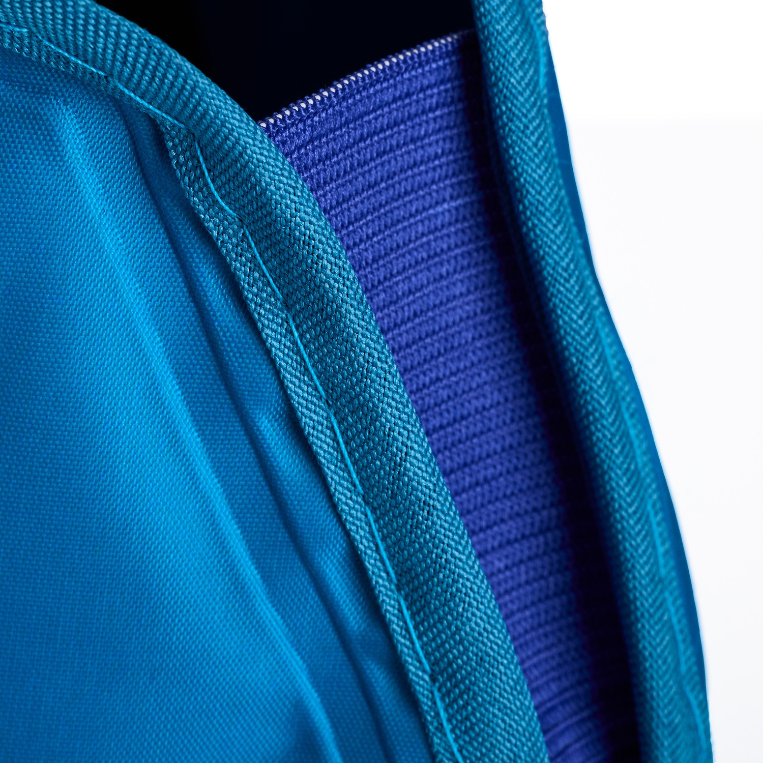 Primo piano di tessuti blu. I bordi turchese incorniciano un tessuto blu scuro strutturato. Lo sfondo è bianco.