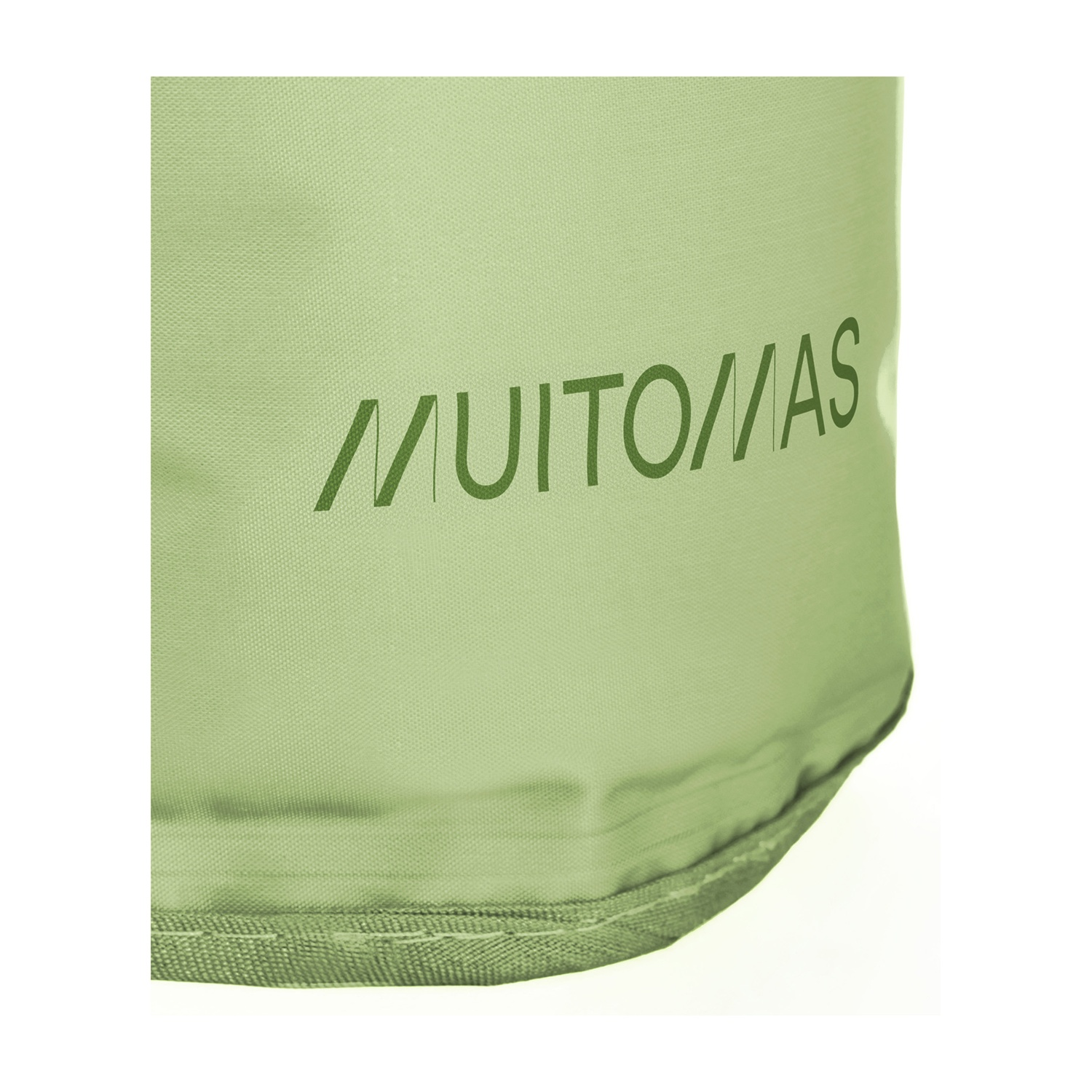 Primo piano di un tessuto verde con la scritta 'MUITO MAS' stampata in una tonalità di verde più scura. Lo sfondo è bianco.