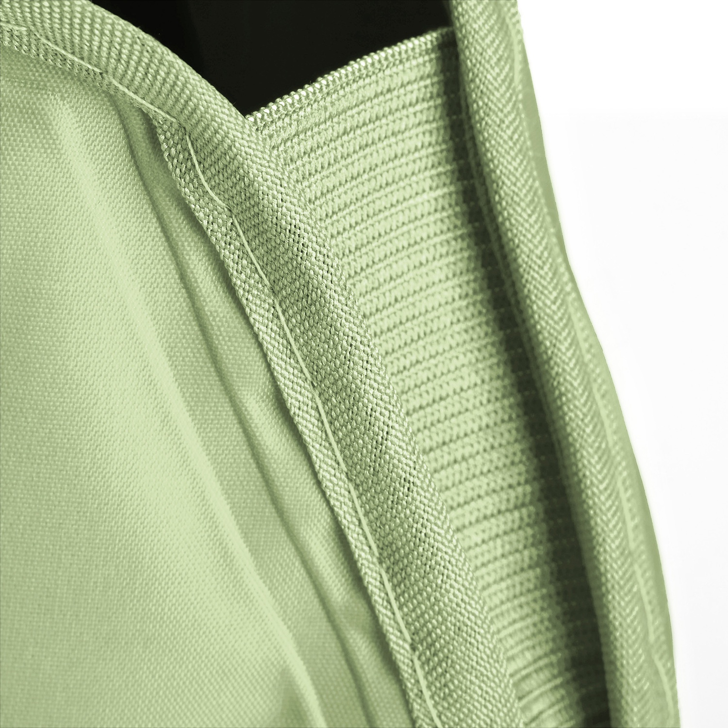 Primo piano di tessuto verde chiaro con superficie strutturata e cuciture visibili. Lo sfondo è bianco e nero.
