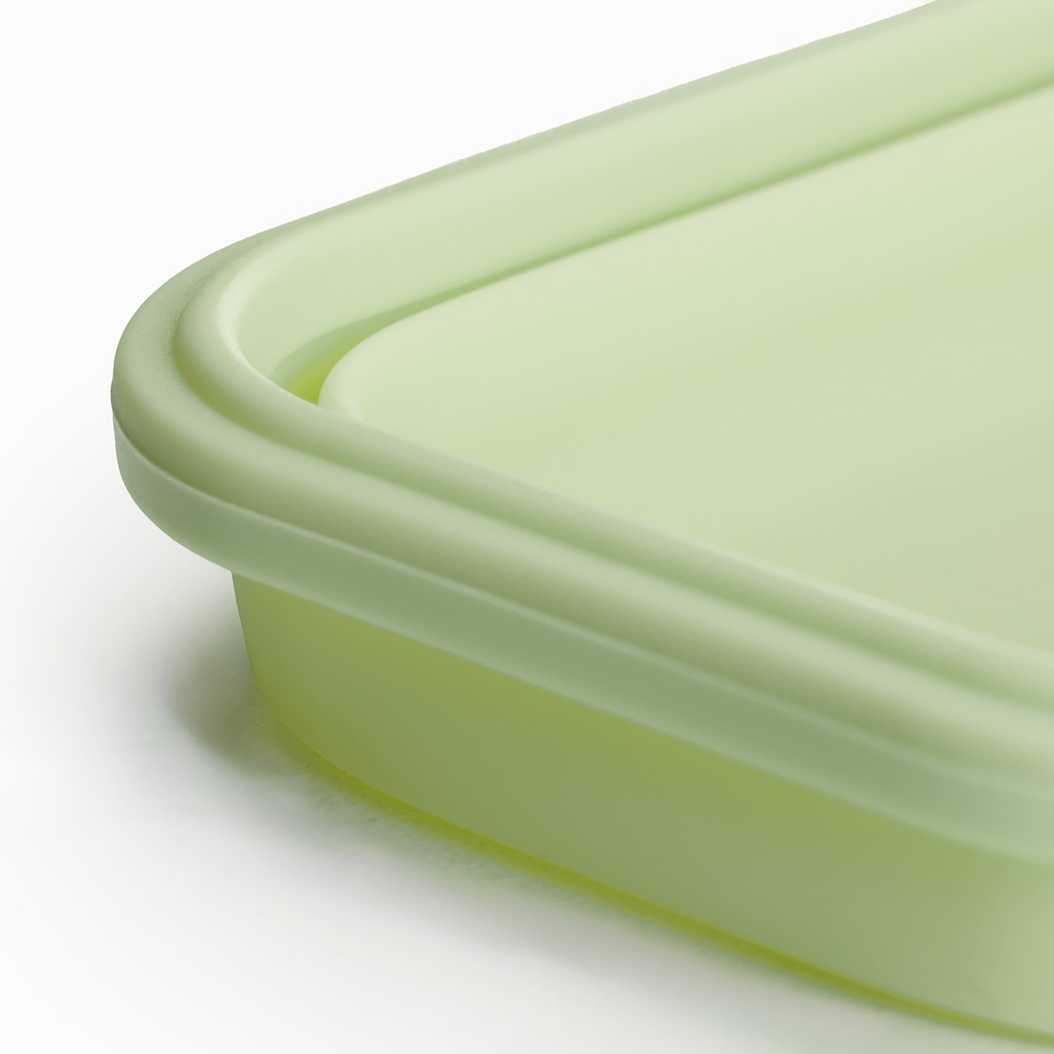 Primo piano di un contenitore verde chiaro. Il coperchio e la base sono visibili su sfondo bianco. Il contenitore ha angoli arrotondati.
