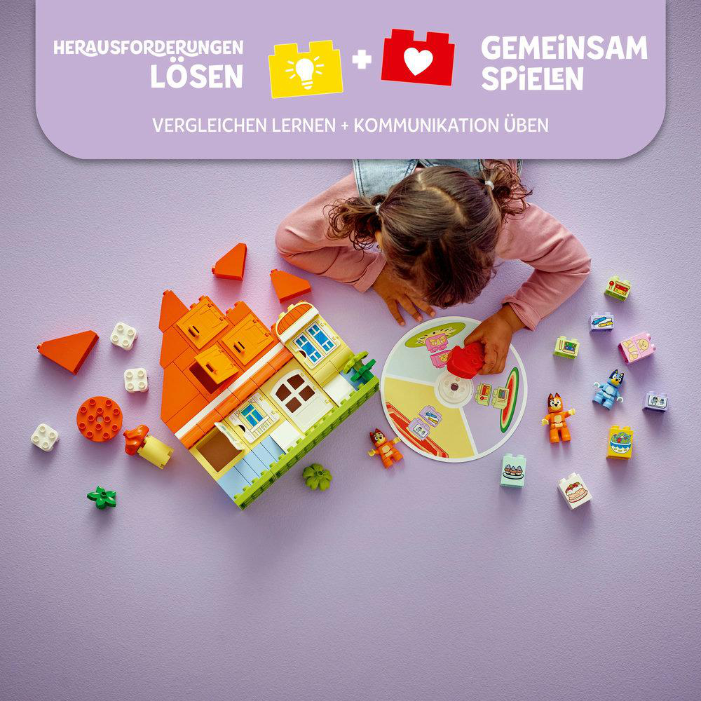 Ein Kind spielt mit bunten Bausteinen, baut ein Haus und platziert Figuren auf einer lila Oberfläche. Text oben weist auf Spiel hin.