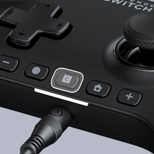 Schwarzer Nintendo Switch-Controller mit Knöpfen, Joystick und eingestecktem Ladekabel.