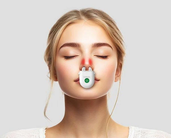 Una mujer con los ojos cerrados tiene un dispositivo médico en la nariz. El dispositivo es blanco con un botón de encendido verde. Su nariz es roja.