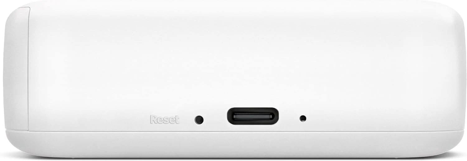 Un dispositivo blanco y rectangular con bordes redondeados. Tiene un botón de reinicio, un puerto y un agujero más pequeño.
