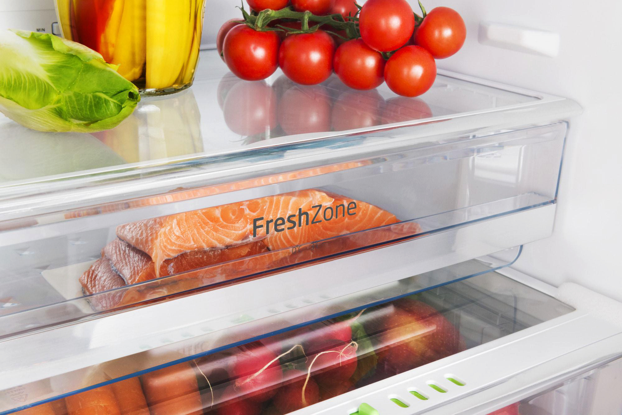 Ein Kühlschrank mit Lachs, Tomaten und Salat. Die 'FreshZone' ist sichtbar. Andere Früchte und Gemüse sind ebenfalls vorhanden.