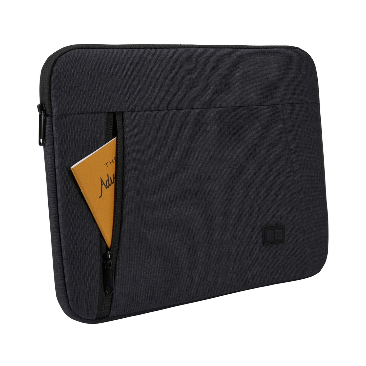 Housse d'ordinateur portable noire avec un petit livre dans la poche avant. Le livre dit 'The Adventure'. Fond blanc.