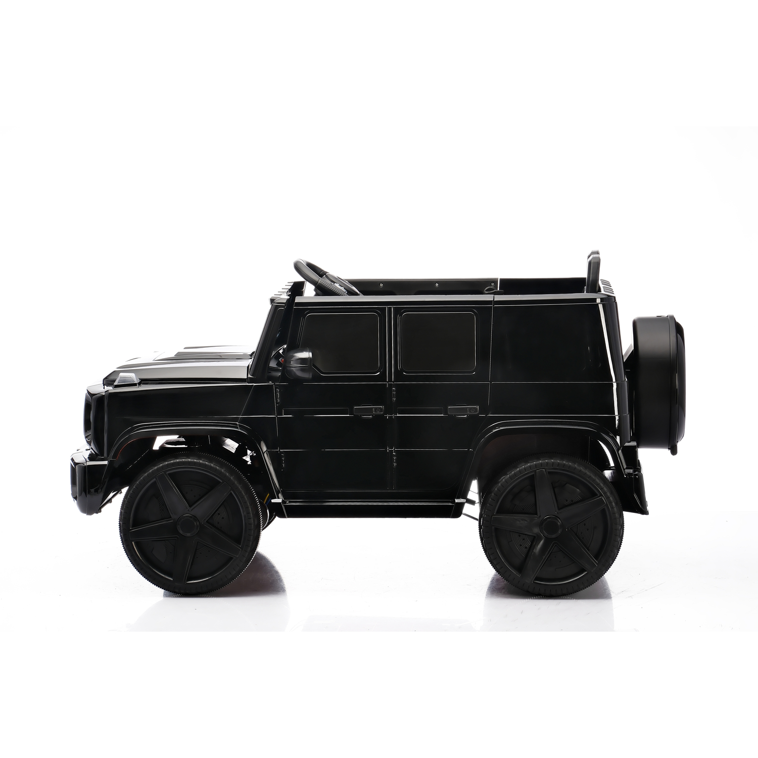 A black toy car, resembling a SUV, is on a white surface. It has large wheels and a spare tire. The background is plain white.