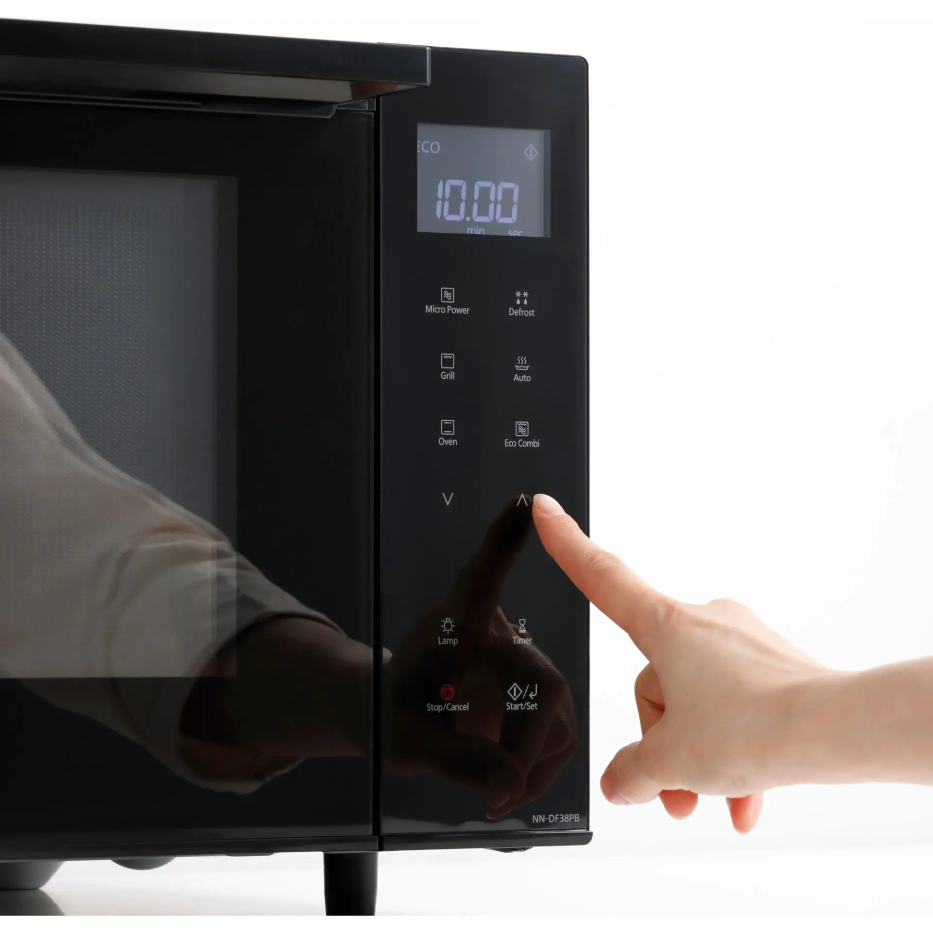 Dłoń dotyka panelu sterowania kuchenką mikrofalową. Wyświetlacz pokazuje 10.00. Przyciski obejmują mikro moc, rozmrażanie, grill, piekarnik i eco combi.
