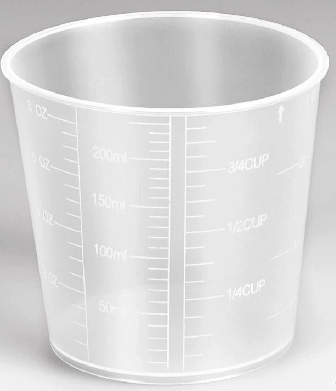 Przezroczysta, plastikowa miarka z oznaczeniami w uncjach, mililitrach i filiżankach. Jest pusta i stoi na białej powierzchni.