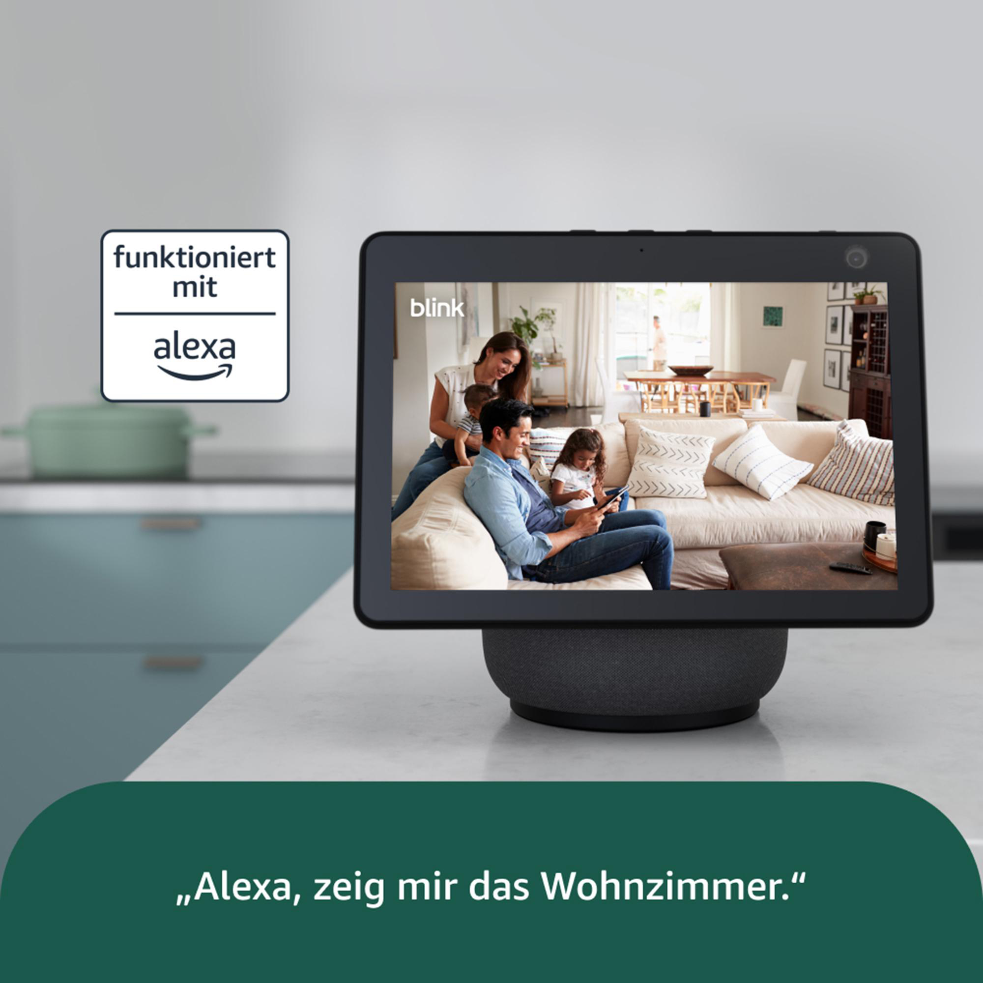 Ein Tablet zeigt eine Familie im Wohnzimmer. Der Text lautet: Alexa, zeig mir das Wohnzimmer. Alexa-Logo sichtbar.
