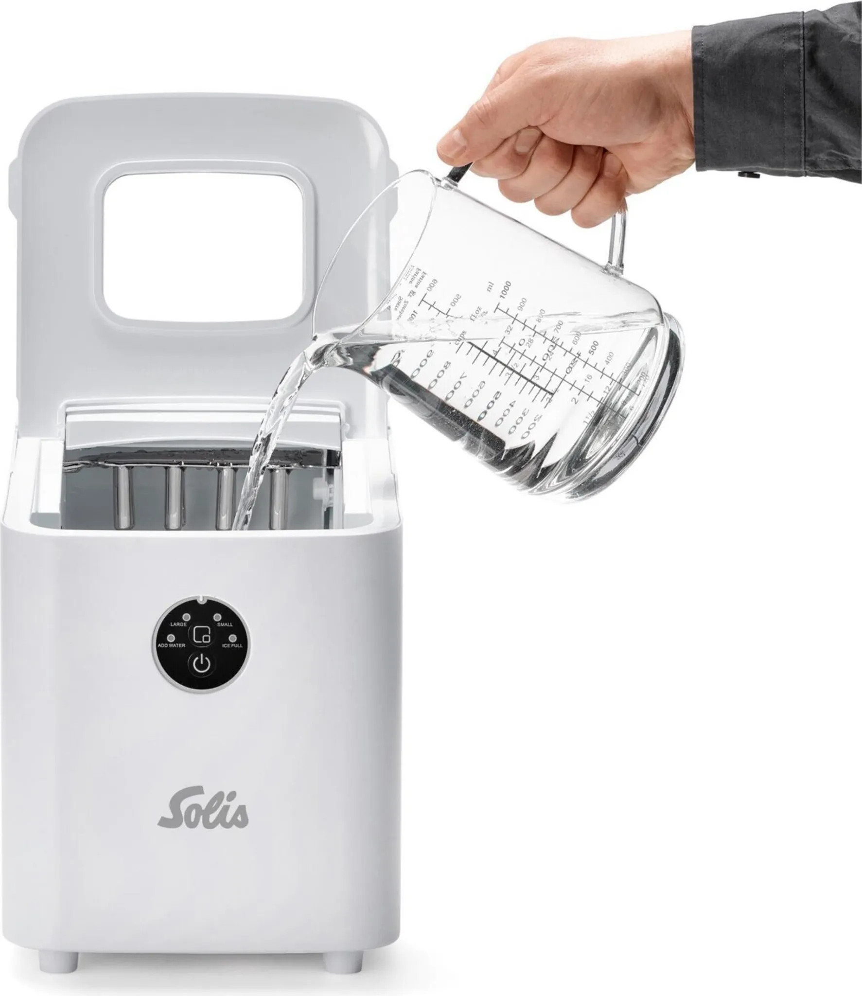 Osoba wlewa wodę z miarki do białej kostkarki. Kostkarka ma markę Solis.