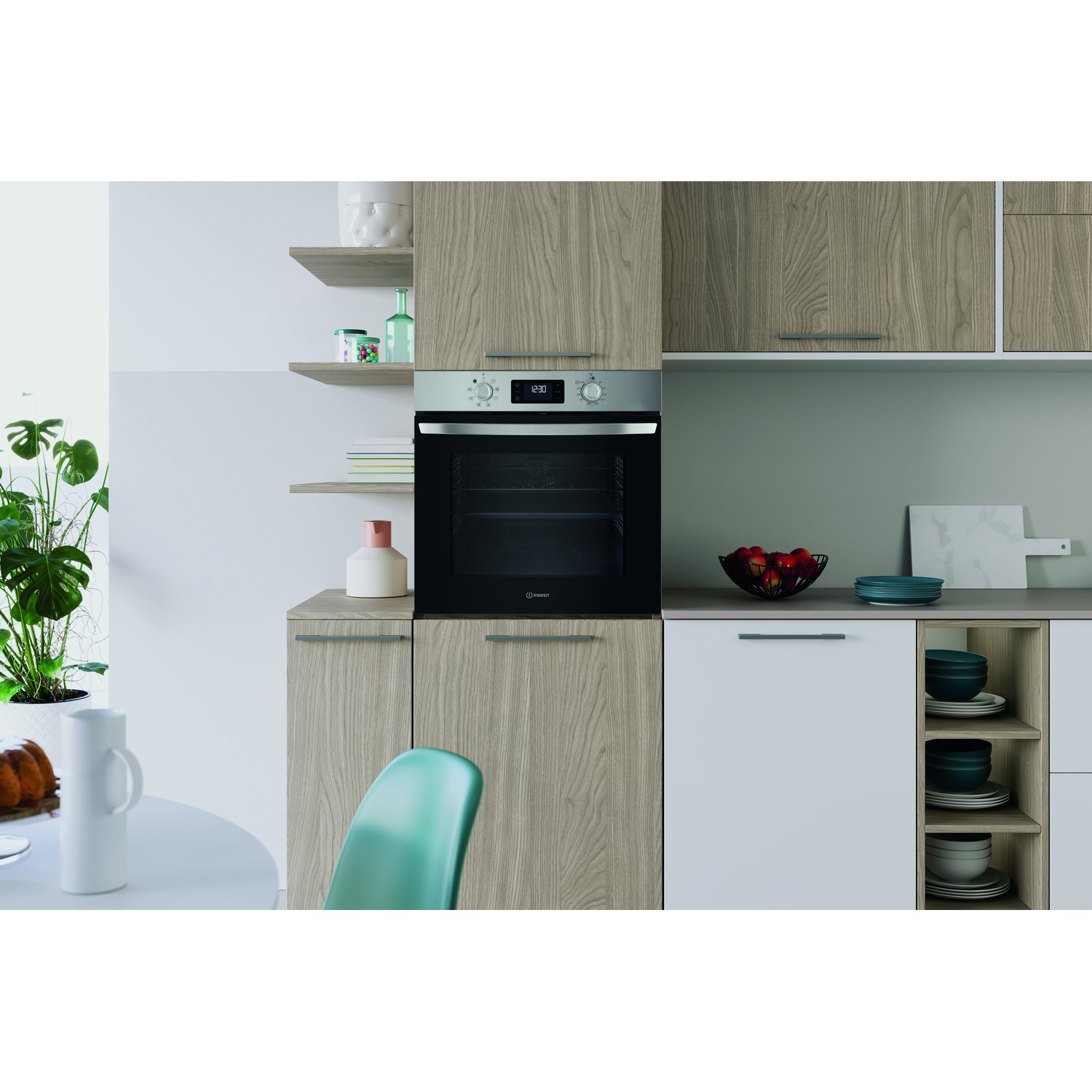 Scena di cucina con forno, mobili in legno, mensole con oggetti, un tavolo e una sedia verde. Sono visibili anche una pianta e piatti.