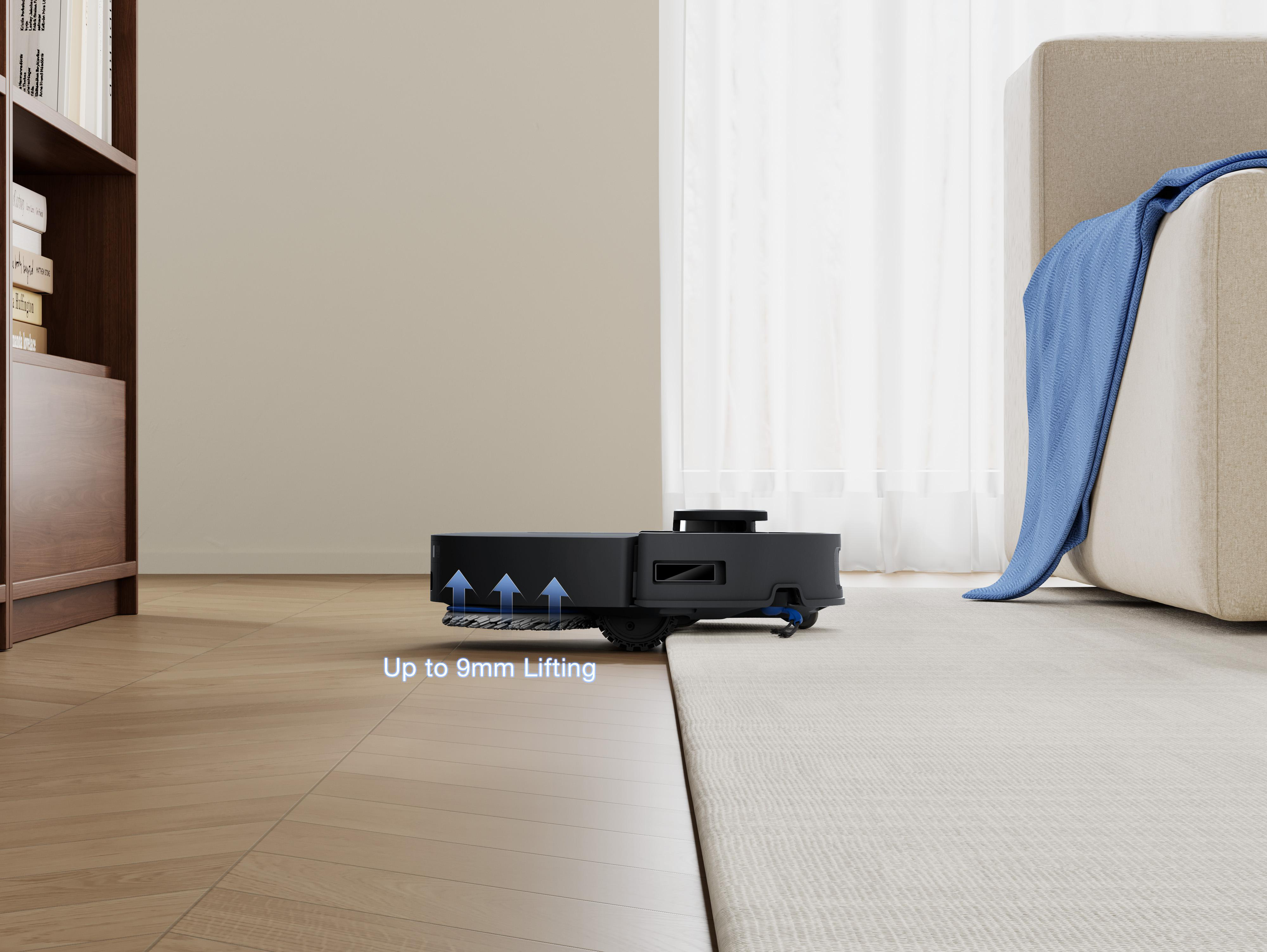 Ein schwarzer Roboter-Staubsauger steht auf einem Teppich. Eine blaue Decke liegt auf einer beigen Couch. Links ein Bücherregal.