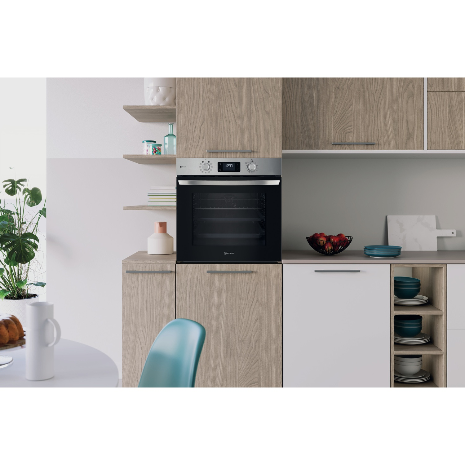 Una cucina moderna con forno a incasso. Sono visibili anche mobili in legno, piani di lavoro bianchi, un tavolo e una pianta.