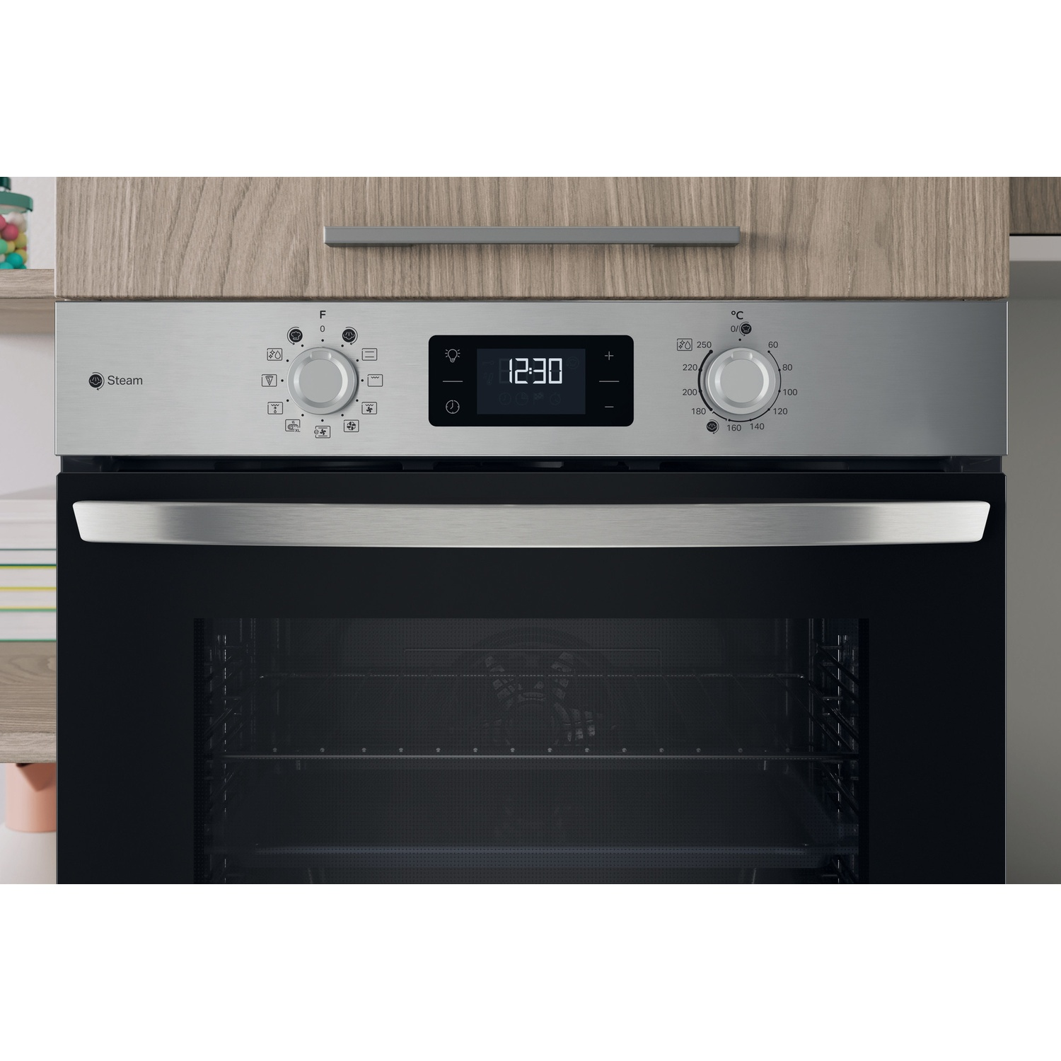 Un forno in acciaio inossidabile con un orologio digitale che mostra le 12:30 e comandi della temperatura. La porta del forno è nera. Pannello di legno sopra.
