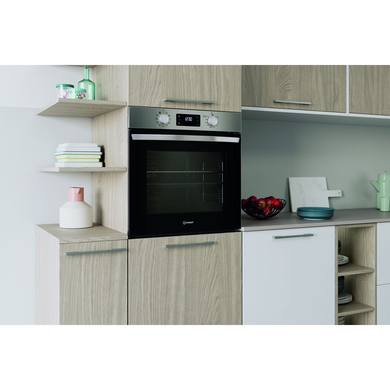 Cucina con mobili in legno, forno, mensole con oggetti e piano con frutta e piatti.