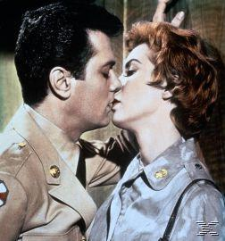 Ein Mann und eine Frau in Uniform küssen sich, Nahaufnahme. Der Mann hat dunkles Haar, die Frau rotes Haar.