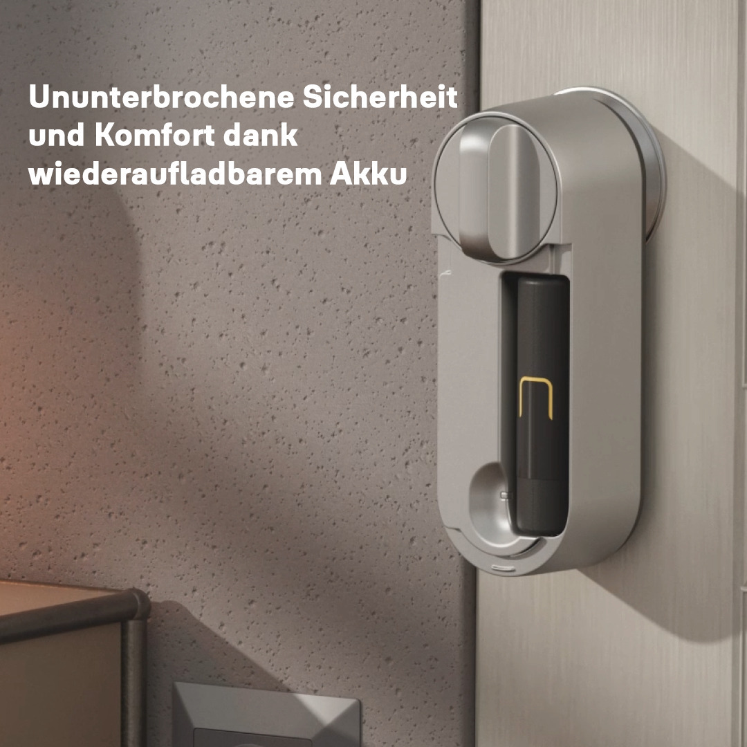 Ein silbernes Smart Lock mit schwarzem Akku und goldfarbenem Ladeanschluss ist an einer Tür befestigt. Der Hintergrund ist eine strukturierte Wand.