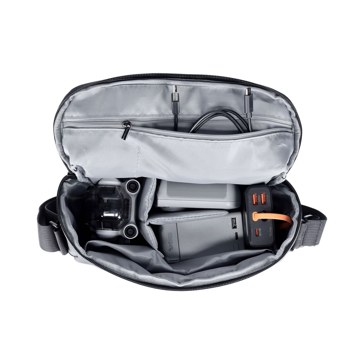 Sac de drone gris ouvert avec drone, chargeur, batteries et câbles. Le sac est noir avec un intérieur gris et une bandoulière.