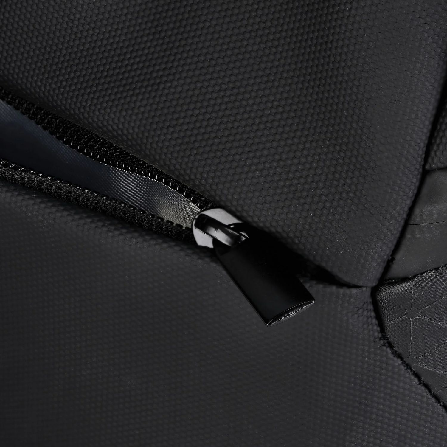 Gros plan sur un sac noir avec une fermeture éclair. La fermeture éclair est ouverte, révélant l'intérieur. Le tissu a une surface texturée.