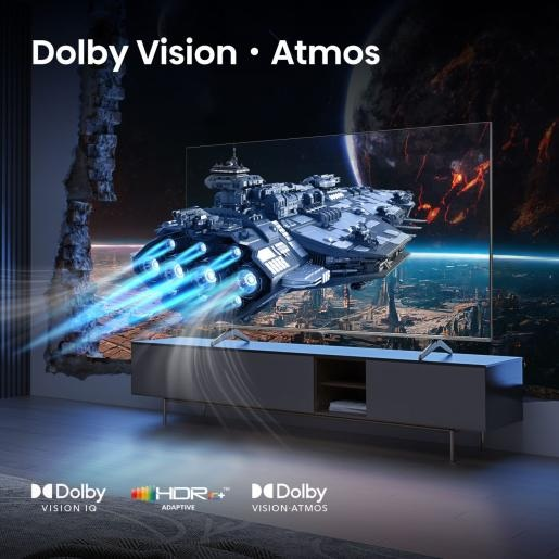 Telewizor wyświetla scenę z statkiem kosmicznym. Telewizor stoi na szarej szafce z logo Dolby Vision i Atmos.