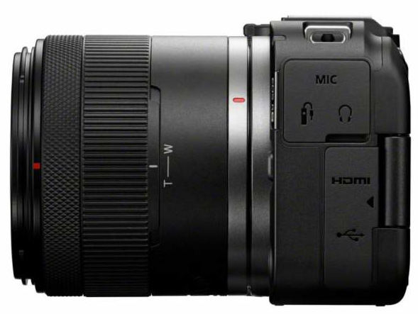 Czarny aparat z dołączonym obiektywem. Obiektyw ma oznaczenia zoomu. Korpus aparatu ma porty na mikrofon, HDMI i USB.